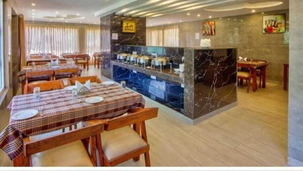A modern dining area with marble countertops and wooden tables. - hotel sainison manali (Manali)