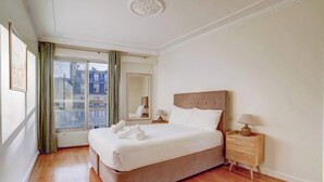 A hotel room with a large bed, a nightstand, a mirror, and a window with curtains.