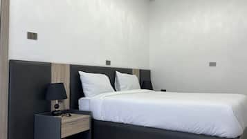 Een moderne hotelkamer met een bed, een nachtkastje met een lamp en een houten paneel aan de muur.