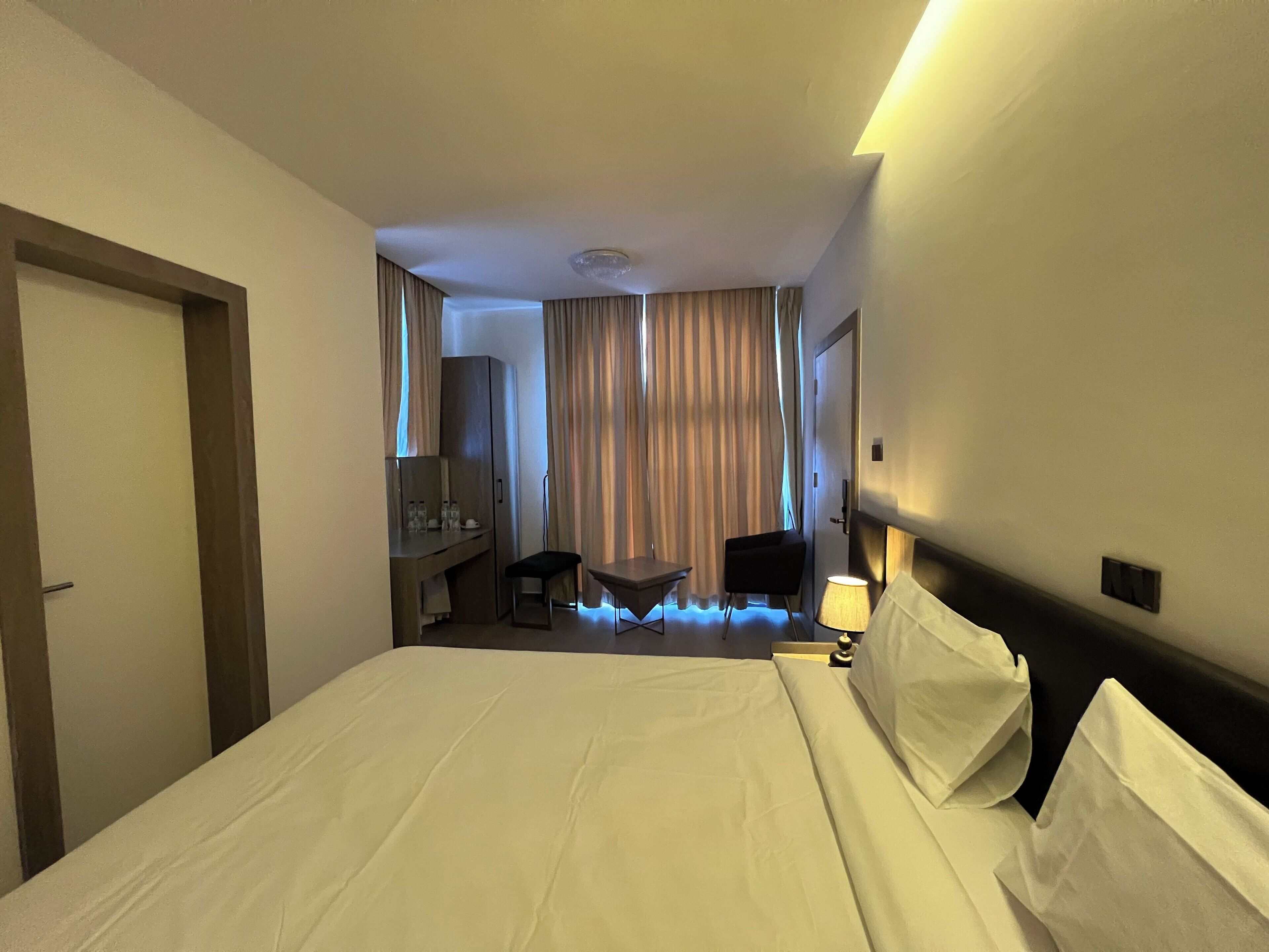 Habitación de hotel con una cama grande, un escritorio, una silla y una lámpara.