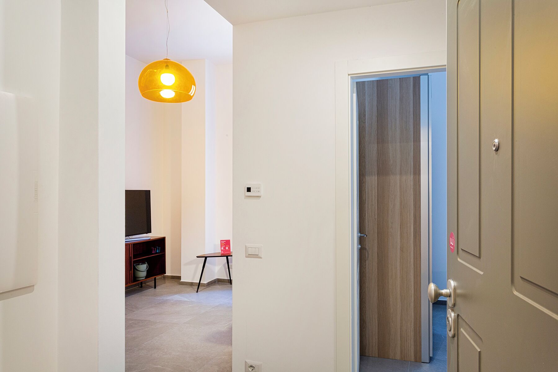 A hallway with a television, a small table, and a door leading to another room.