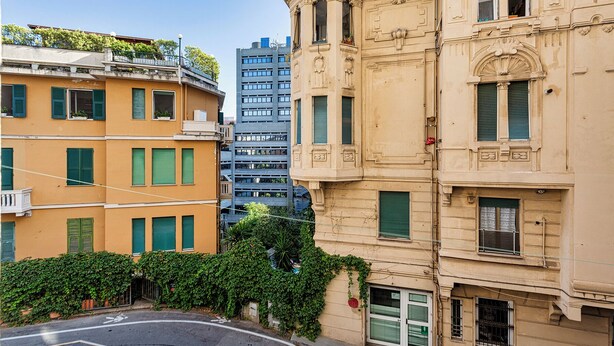 A street view with buildings, including a beige building with green shutters and a modern high-rise in the background. - Carignano Sweet Home by Wonderful Italy (Genoa)