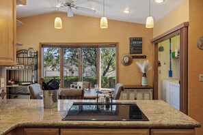 A kitchen with a granite countertop, a dining area with a table and chairs, a large window with a view, and a ceiling fan. - Prescott Golf Upscale Oasis Comfort Dog Friendly (Dewey)
