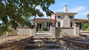 Une maison à deux étages avec une façade en pierre, un porche à l’avant avec des marches et un patio.