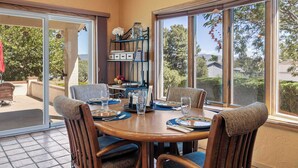 Un espace repas avec une table ronde, des chaises et une vue dégagée grâce à de grandes fenêtres.