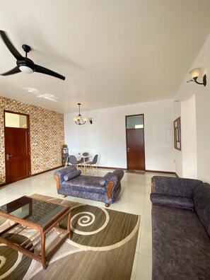 A spacious living room with a ceiling fan, two sofas, a coffee table, and a patterned rug. - Zanzibar manolo 4 (Paje)