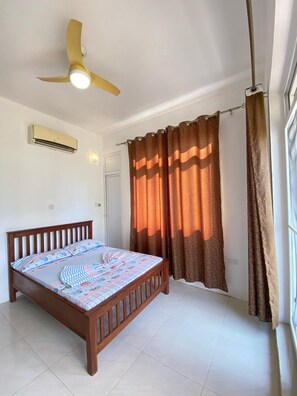A bedroom with a bed, a ceiling fan, an air conditioner, and curtains. - Zanzibar manolo 4 (Paje)