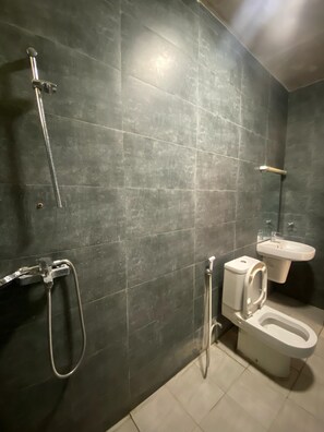A bathroom with dark tiles, a shower, a toilet, and a sink. - Zanzibar manolo 4 (Paje)