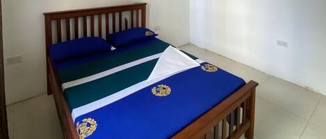 A bedroom with a wooden bed, a ceiling fan, an air conditioner, and a wall-mounted light.