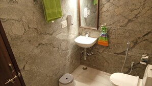A bathroom with a marble wall, a sink, a toilet, and a bidet.