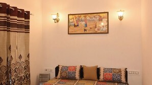 A bedroom with a bed, a ceiling fan, patterned curtains, a quilt, and wall-mounted lights.