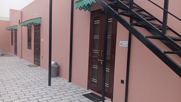 A building with pink walls, a staircase, and a tiled entrance area.