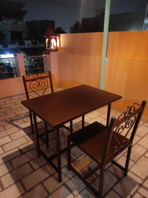 Um pátio com uma mesa, cadeiras, corrimão e um candeeiro.