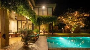 A modern house with a swimming pool, outdoor seating, and a well-lit garden at night. - Villa Tranquil Waters (Negombo)