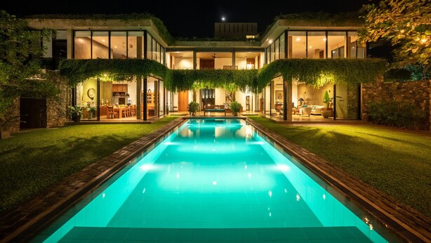 A modern house with a swimming pool, glass walls, and a well-lit interior. - Villa Tranquil Waters (Negombo)