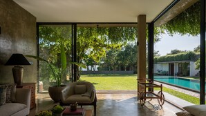 A modern living room with a large glass door leading to a pool and garden. - Villa Tranquil Waters (Negombo)