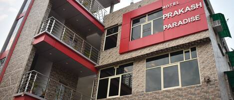 Un hotel de varios pisos con una fachada destacada en rojo y gris, balcones y ventanas amplias.