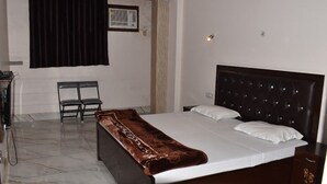 Un dormitorio con una cama grande, una silla, un escritorio y una ventana con cortinas.