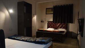 Un dormitorio con cama, armario, escritorio y ventana con cortinas.