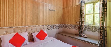 A bedroom with a bed, a bench, a window with curtains, and a wooden wall.