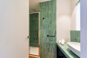 Une salle de bain avec une douche, un lavabo et un miroir.