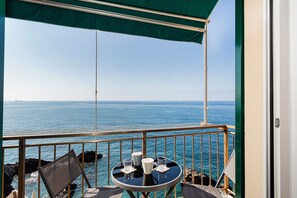 Un balcón con mesa, sillas y vista al mar.