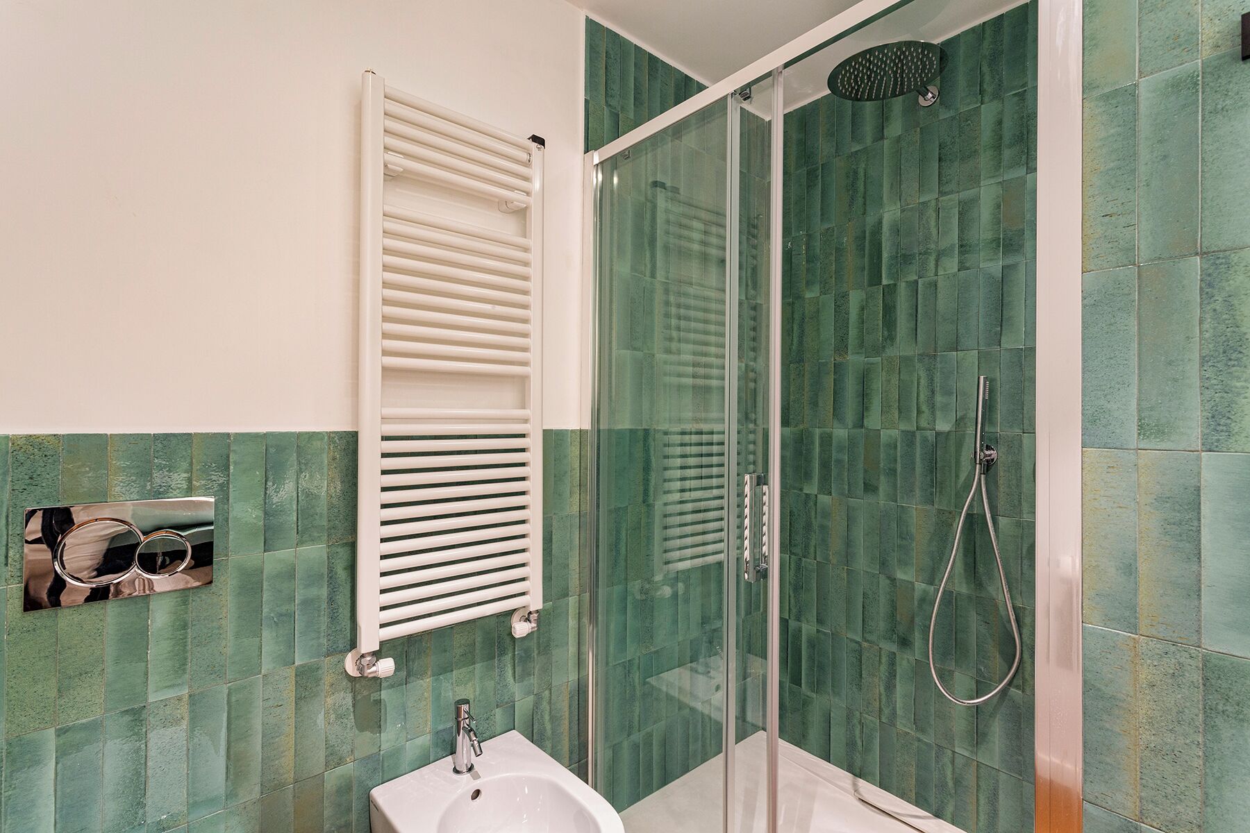 Une salle de bain avec une douche à parois de verre, un lavabo blanc et un porte-serviettes.