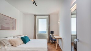 Een hotelkamer met een bed, een bureau, een stoel, een raam met uitzicht en een grote spiegel.