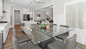 Une cuisine moderne dotée d’un îlot central, d’appareils électroménagers en acier inoxydable et de luminaires suspendus.