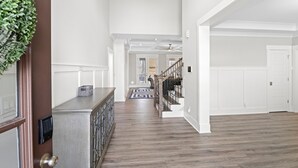 Un hall d’entrée spacieux, doté d’un plancher en bois, d’un banc intégré et d’un ventilateur de plafond.