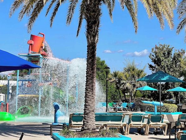 A water park with a water slide, seating areas, and palm trees.