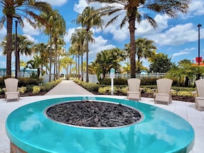 A pool area with a circular hot tub surrounded by lounge chairs, palm trees, and a clear sky.