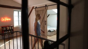 Una habitación con una cama, una estantería y un letrero de neón que dice "La Ferme".