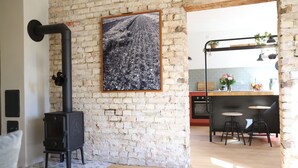 Una cocina rústica con pared de ladrillo, estufa negra y una foto enmarcada encima.