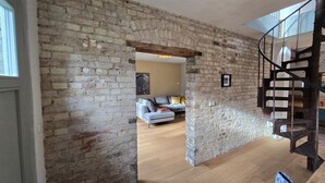 Una habitación con paredes de ladrillo visto, una escalera de madera y una zona de estar moderna con sofá y una mesa de centro.