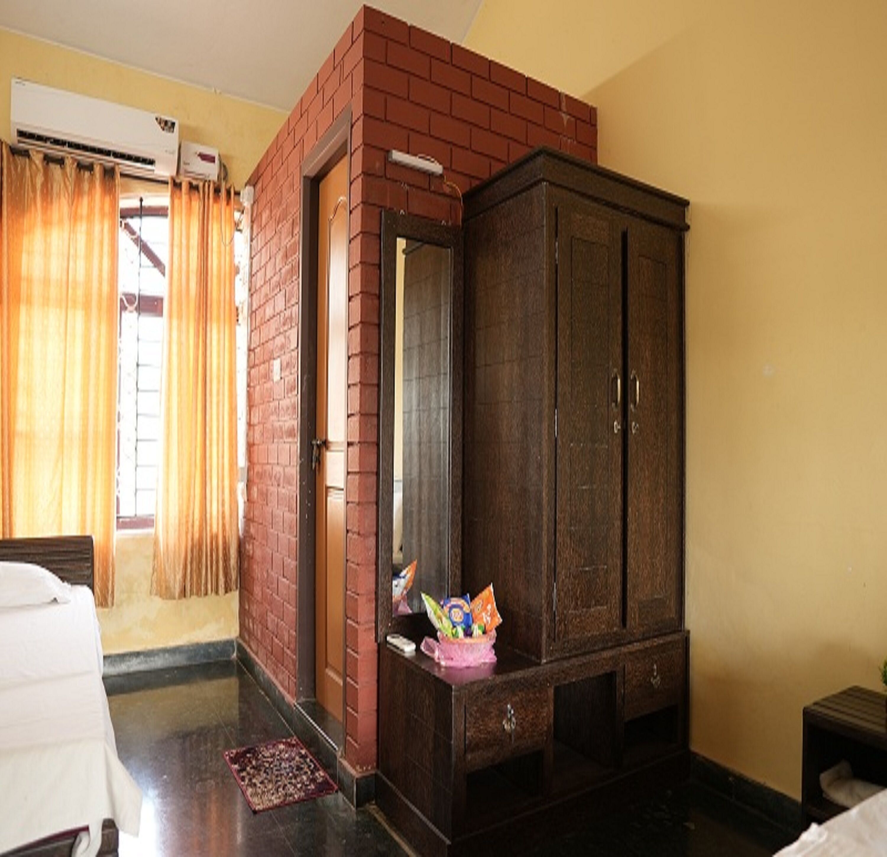 A room with a brick partition, a wardrobe, a bed, and a small table with a basket.