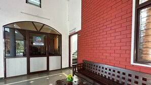 Un área de recepción con un banco, una pequeña mesa con una planta y una pared de ladrillo rojo.