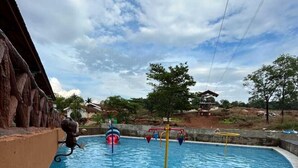 Una piscina con tobogán y una pequeña zona de juegos acuáticos.
