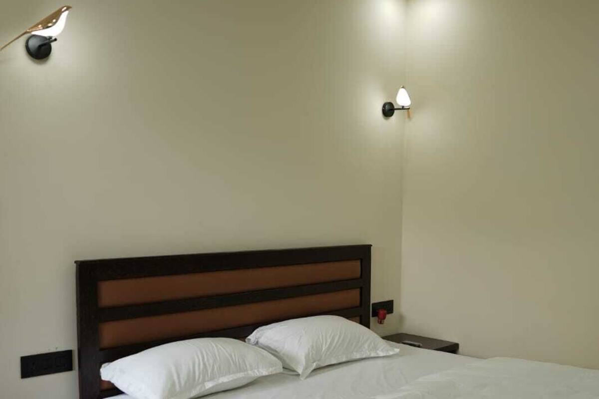 Un dormitorio con una cama grande, cabecera de madera, dos mesitas de noche y dos lámparas de pared.