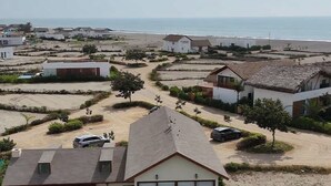 Un quartier résidentiel avec des maisons, une piscine et une plage en arrière-plan.
