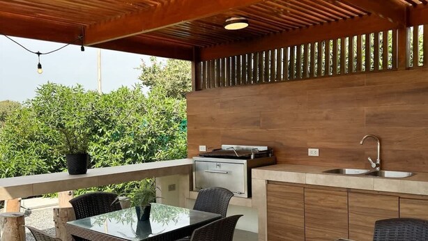 Un espace cuisine extérieur comprenant une table et des chaises, un évier encastré et un barbecue.