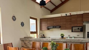 Une cuisine moderne avec des meubles en bois, un plan de travail en granit et un coin repas comprenant des chaises en bois et un canapé en cuir.