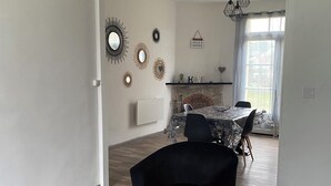 A modern living room with a fireplace, black leather sofa, and a dining area with a table and chairs.