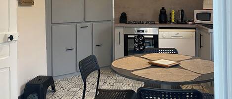 Una cocina moderna con una mesa de comedor redonda, sillas negras, una estufa a gas, un microondas y un horno empotrado.
