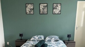 A bedroom with a bed, two bedside tables, and three wall-mounted artworks.