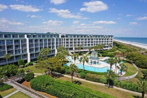 A hotel with multiple floors, a pool area, and a beach view.