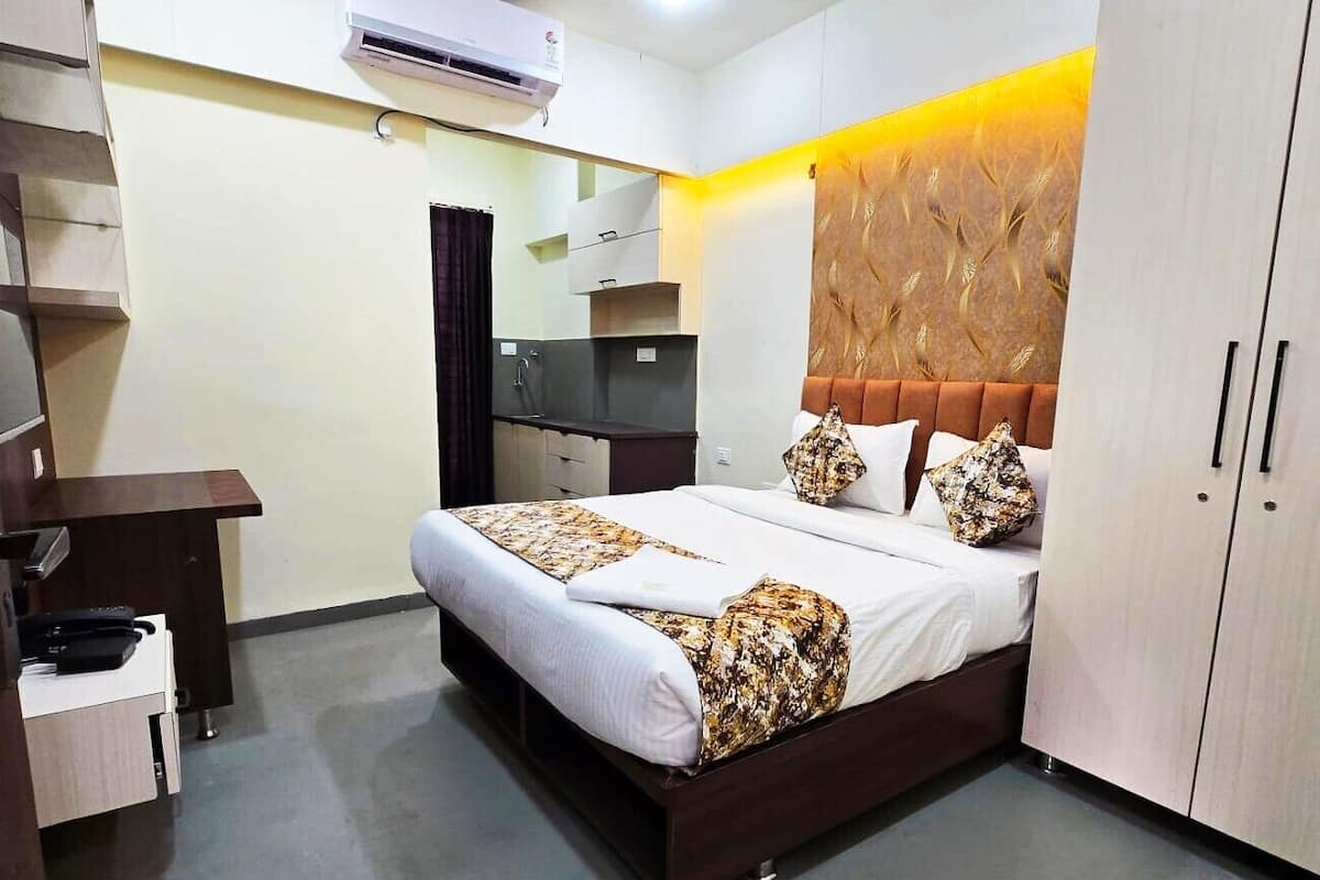 A hotel room with a bed, a desk, a wardrobe, and a mirror.