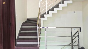 Eine Treppe mit Metallgeländer, einer Holztür und einer hellen Wand.