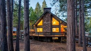 A cabin with a stone facade, large windows, and a deck.