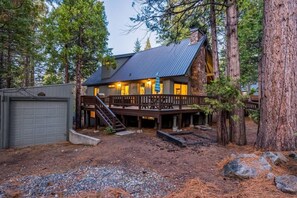 A cabin with a wooden deck, a staircase, and a garage. - Kokanee Hideaway | 5BR w/ Epic Game Room (Shaver Lake)